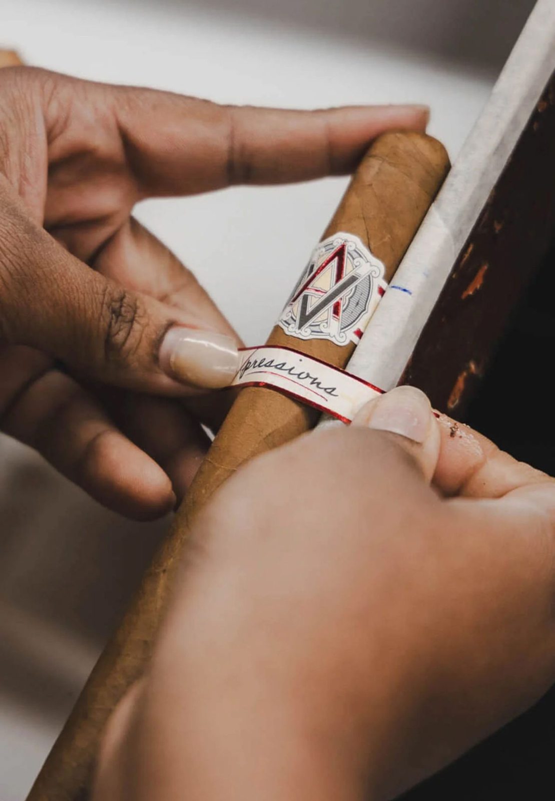 Hands unwrapping an AVO cigar